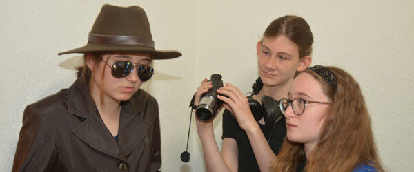 Jugendliche der Filmbrugg spielen eine Szene mit Hut, Sonnenbrille und Videokamera